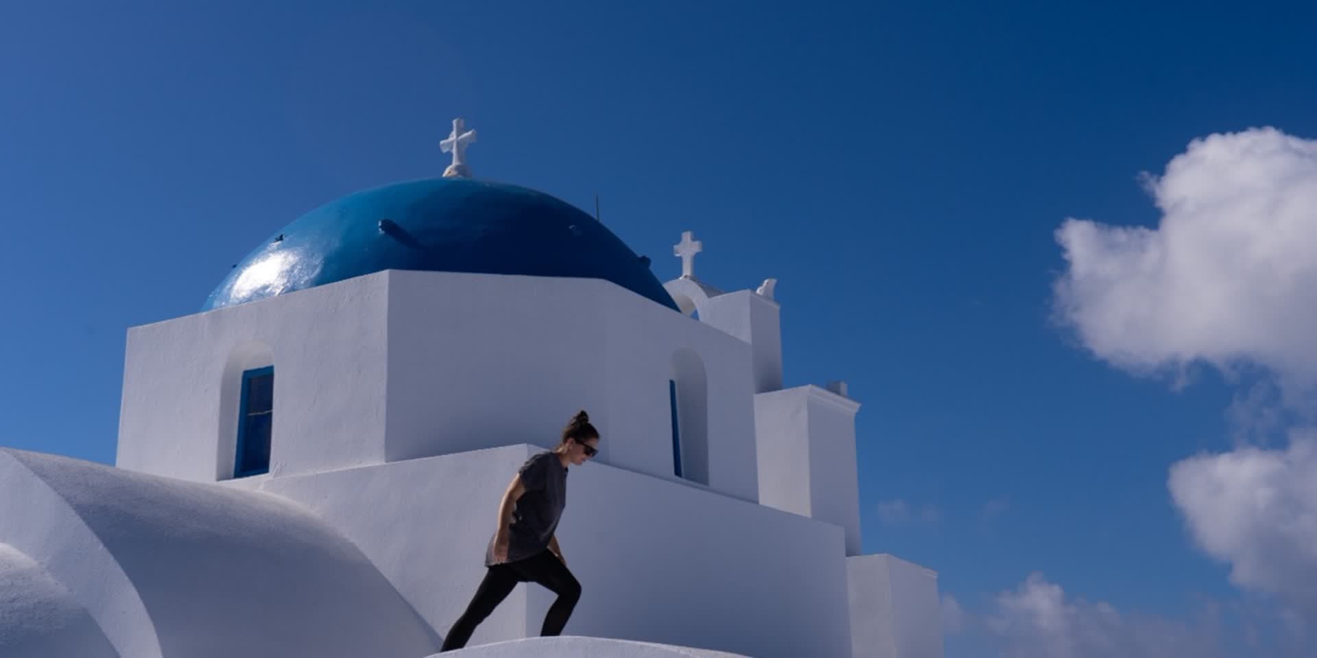Frau vor einer weiss-blauen Kirche auf einer griechischen Insel